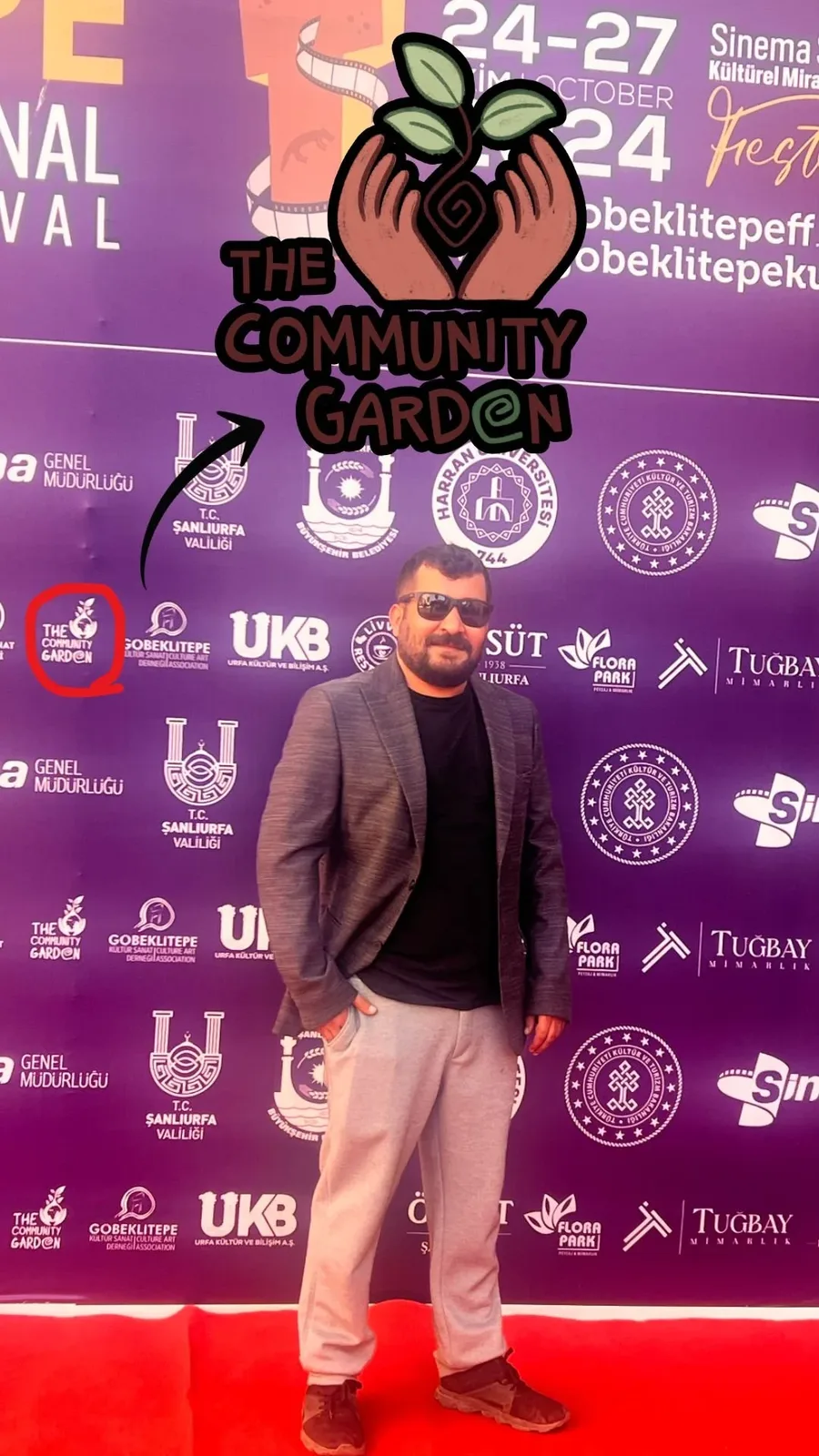 Ramazan Aygat at the festival sponsor wall with The Community Garden logo