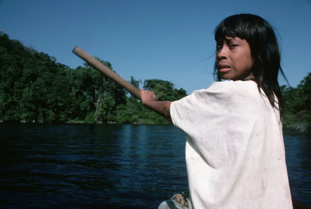 A young Lacandón woman paddling a canoe on the river